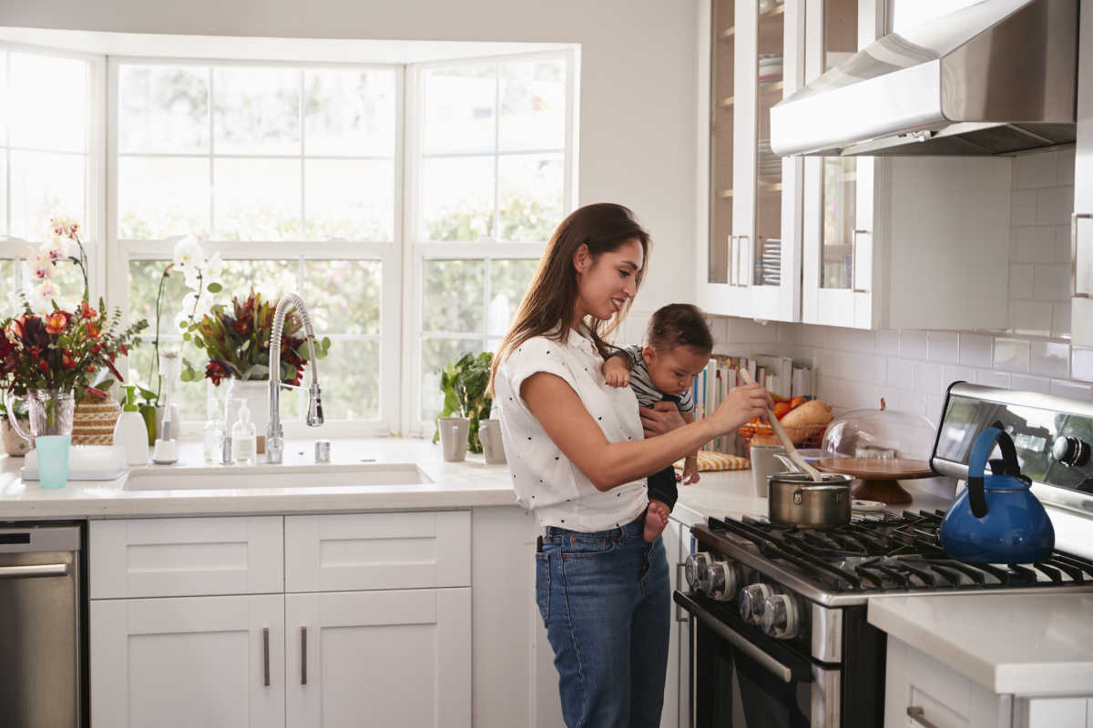 Mom stirring pot and holding baby