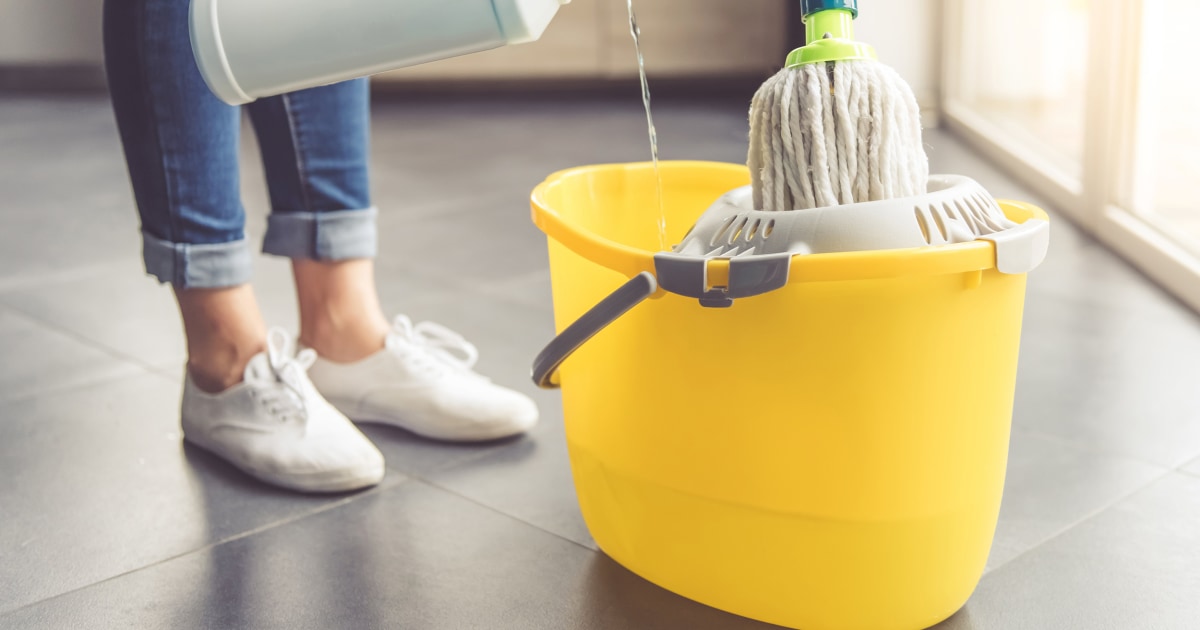 a woman standing over a mop bucket